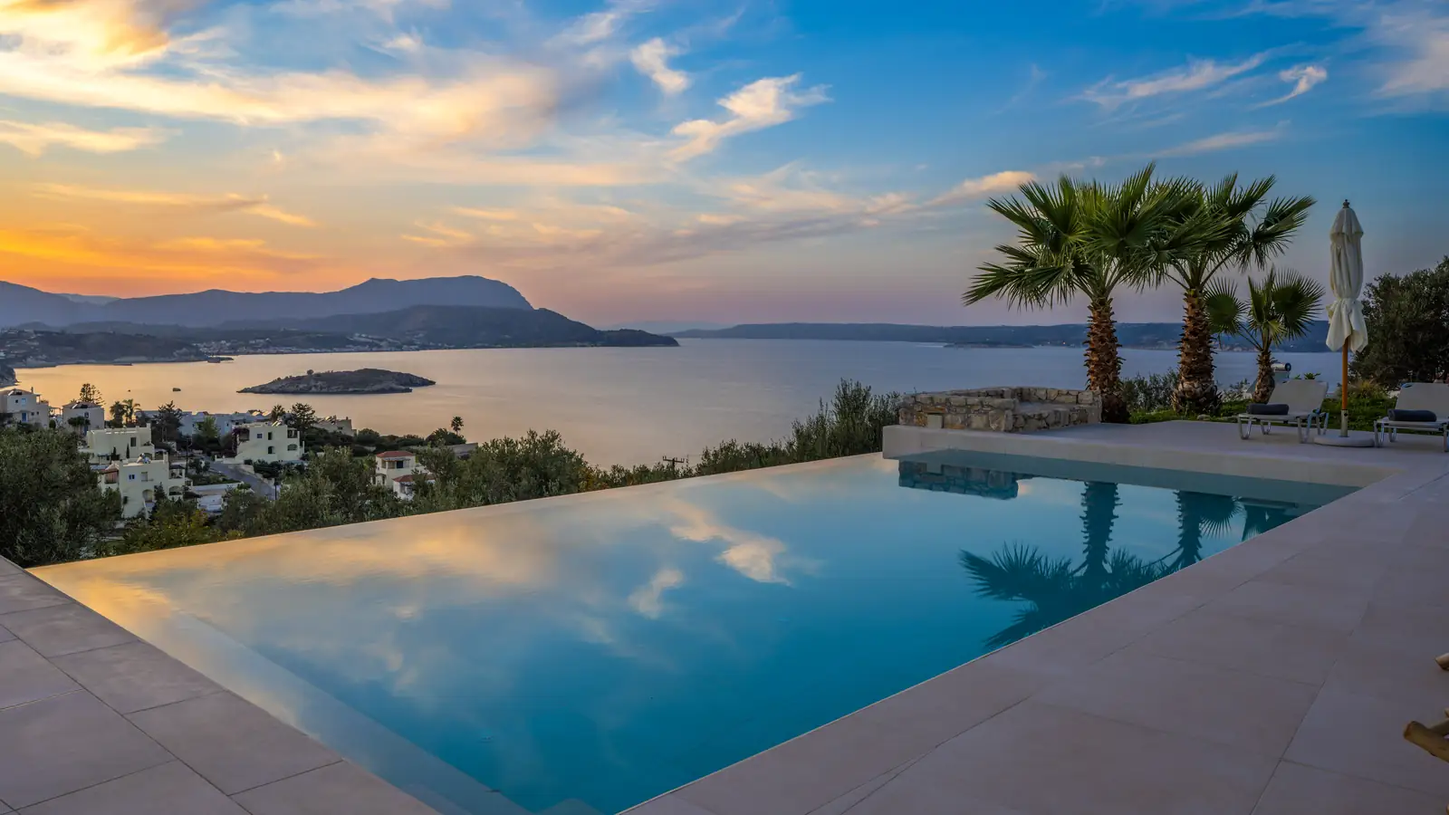 The infinity pool at sunset, with the sea and the mountains behind